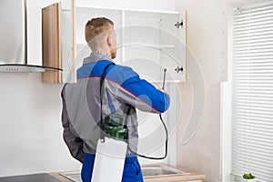 Worker Spraying Insecticide On Shelf photo