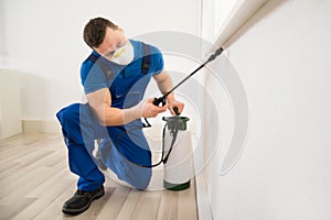 Worker Spraying Pesticide On Window Corner