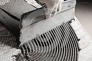 Worker spreading concrete on ceramic tile with spatula