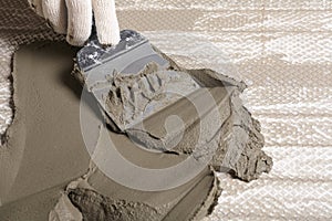 Worker spreading concrete on ceramic tile with spatula, closeup