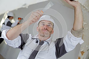 worker spreading plaster on ceiling at construction site