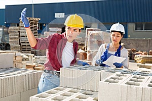 Worker stacking bricks in warehouse of building materials on an open-air site