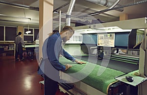 Worker standing near cutting machine in workshop of footwear manufacturing factory