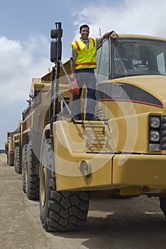 Worker Standing On Truck At Landfill Site