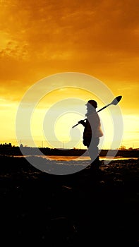 Worker stands holding a shovel.