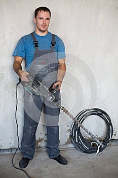 A worker stands near a wall with a large
