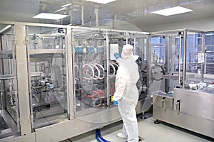 worker in sterile protective clothing in a clean room of a pharamzie company operates the technical plant for the production of d