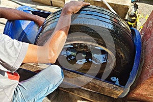 Worker submerge tyre into water container for bubble to check point of punctured