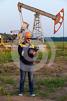 A worker with a tablet monitors the serviceability of oil pumps