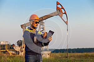 A worker with a tablet monitors the serviceability of oil pumps