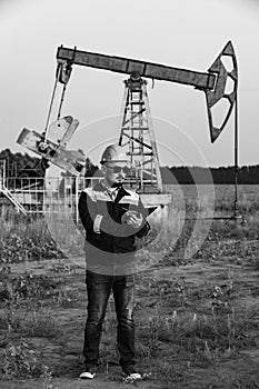 A worker with a tablet monitors the serviceability of oil pumps. Black and white photography