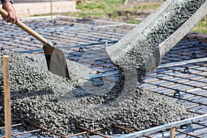 Worker takes concrete from a mixer tray with a shovel