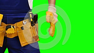Worker takes out a screwdriver from his construction belt. Green screen. Close up
