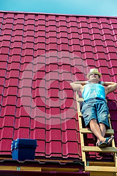 A worker takes a sun bath on the roof of the house during