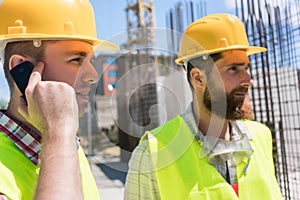 Worker talking on mobile phone during work on a construction site
