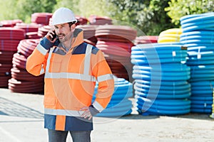 Worker on telephone in building materials yard