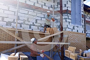 A worker throws bricks at another worker, construction work in a private area, wooden scaffolding near the walls