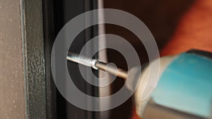 Worker tightening screw with screwdriver, installing window frame