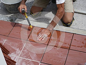 Worker tiler metre laying tiles intent in his work
