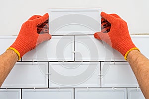 Worker is tiling the white tiles on the kitchen wall. Concept of a kitchen renovation.