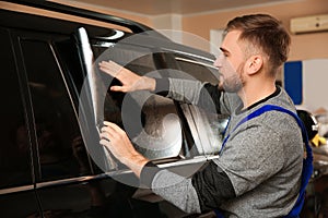 Worker tinting car window with foil