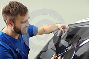 Worker tinting car window with foil