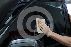 Worker tinting car window with foil in workshop