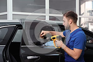 Worker tinting car window with heat gun