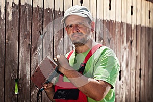 Worker about to scrape away the old paint from a wooden fence