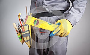 Worker with a tool belt holding level. Construction tools