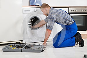 Worker With Toolbox Repairing Washing Machine