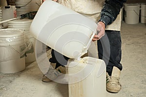 Worker Transfering Liquid Plaster Resin into Plastic Container