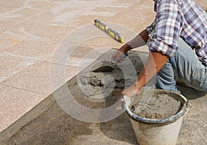 worker with trowel and mixed mortar in a bucket to tiled on the floor