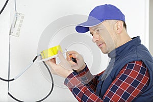 worker trying to install wires on wall