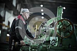 worker turner operating lathe machine at industrial manufacturing factory
