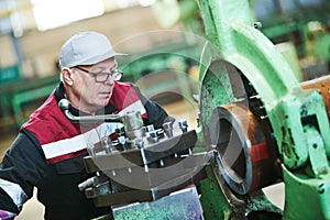 worker turner operating lathe machine at industrial manufacturing factory