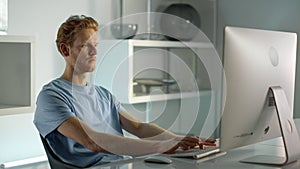 IT worker typing desktop computer in home office closeup. Remote workplace view