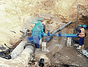 Worker underground for reconstrucion of drink water system. Technical expert at gate valve