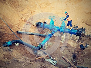 Worker underground for reconstrucion of drink water system. Technical expert at gate valve