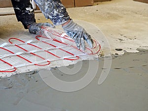 A worker unfolds a roll of warm electric floor for laying under a cement screed