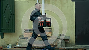 A worker in uniform is carrying cargoto the warehouse.Loader man is deliver the goods.Warehouse worker is holding heavy
