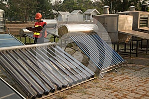 The worker in uniform and helmet checks concentrating Solar Power with Flat Plat collector and Evacuum Tube Collector.