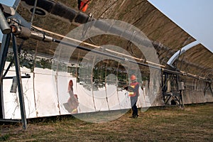 The worker in uniform and helmet checks Solar Parabolic Troughs.