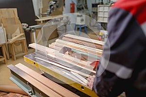 An employee holds a board by cutting with a special tool. Rear view angle