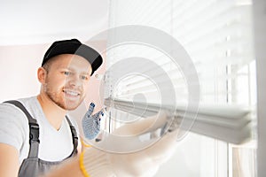 Worker in uniform installing blinds on plastic upvc window