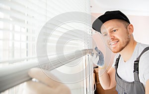 Worker in uniform installing blinds on plastic upvc window