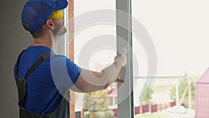 Worker in uniform installs handle of cottage plastic window