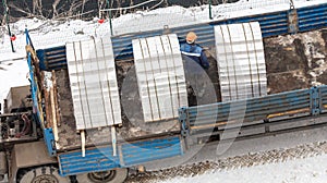 A worker is unloading bricks in a truck at a construction site
