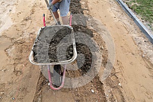 A worker unloads concrete from a wheelbarrow