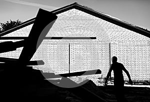 A worker unloads on the construction of wooden boards on a background of a brick wall. Black and white photo of high contrast.